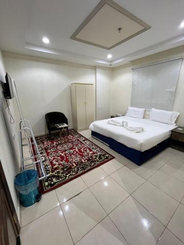 a bedroom with a bed and a chair and a rug at AL-Diyafh Hotel in Az Zāhir