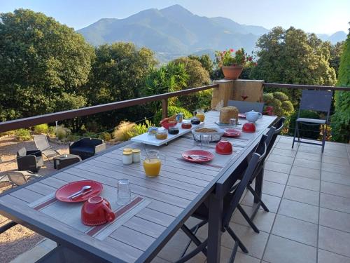 a wooden table with red plates and drinks on a balcony at Chez Nat et JC in Eccica-Suarella
