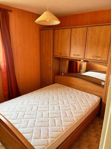 Cette petite chambre comprend un lit et des placards en bois. dans l'établissement Le Volvire 31, au Cap d'Agde