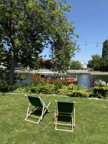 two chairs sitting on the grass next to a river at AtmosferA in Bydgoszcz
