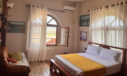 a bedroom with a bed and a chair and a window at Vila Shehi Guesthouse and Winery in Tirana