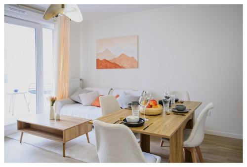 ein Wohnzimmer mit einem Tisch und einem Sofa in der Unterkunft Paisible 3 pièces, proche de Paris avec parking in Romainville