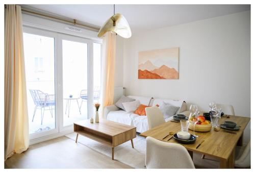 ein Wohnzimmer mit einem Tisch und einem Sofa in der Unterkunft Paisible 3 pièces, proche de Paris avec parking in Romainville