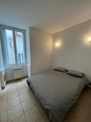 une chambre avec un lit et une grande fenêtre dans l'établissement Appartement 4 personnes centre historique Aubenas, à Aubenas