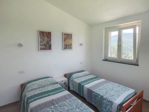 two beds in a room with a window at La casa delle Mogge in Piazza
