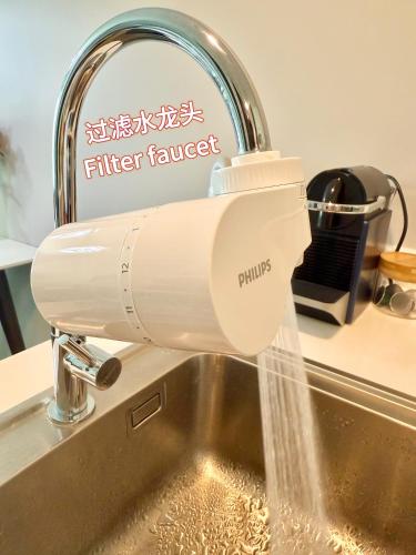 a kitchen faucet pouring water into a sink at The Astra Sky River Chiang Mai 三卧两卫宜居6人 无边泳池 热水浴缸 乳胶床垫 in Chiang Mai