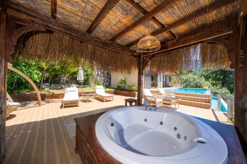 a bath tub in a villa with a swimming pool at Lissiya Hotel in Faralya