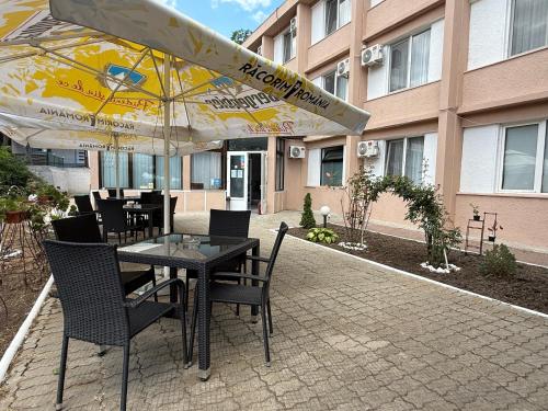 a table and chairs with an umbrella in front of a building at Hotel Decebal Eforie Nord in Eforie Nord