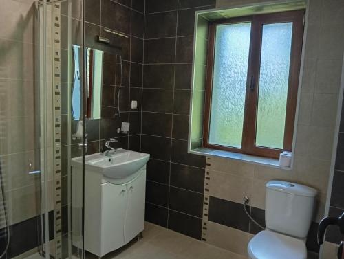 a bathroom with a sink and a toilet and a window at Къща за гости ЧЕРИ in Tryavna