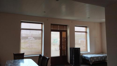 a room with three windows and a table and chairs at Welcome to Ashtarak in Ashtarak