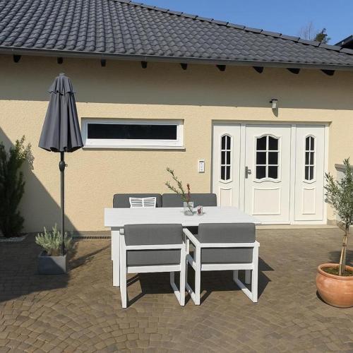 a table and two chairs and an umbrella in front of a house at Ü Villa Single Apartment mit Grillmöglichkeit in Hirschaid
