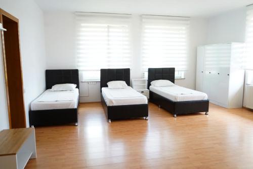 three beds in a room with wooden floors and windows at Hotel AKSU in Bucharest