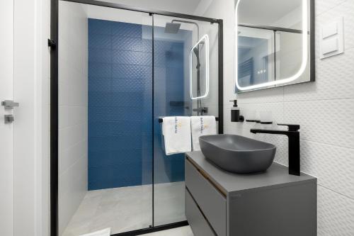 een badkamer met een wastafel en een glazen douche bij Apartamenty Baltic Marina in Międzywodzie