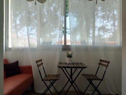 deux chaises et une table devant une fenêtre dans l'établissement Cosy au bassin, à La Teste-de-Buch