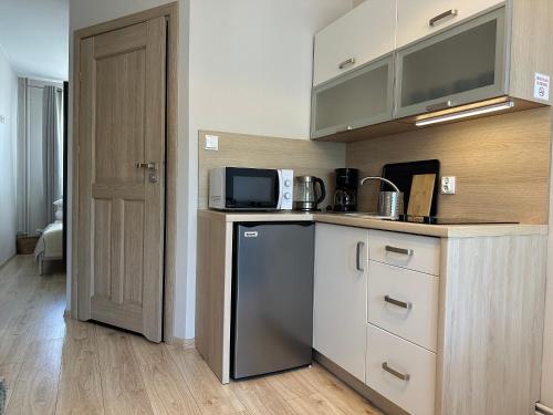 a kitchen with a counter with a refrigerator and a microwave at APARTAMENTY LAVENDERIA z widokiem na Górę Parkową, blisko centrum in Kudowa-Zdrój
