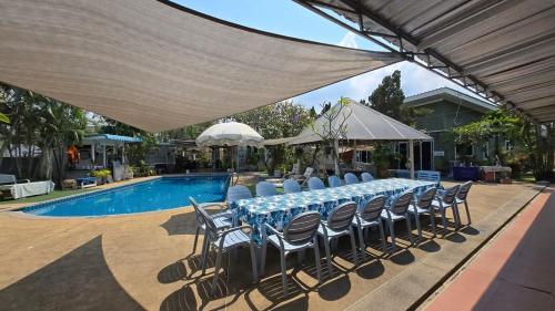a table and chairs under a canopy next to a pool at Willkris Resort วิลล์คริส รีสอร์ท in Bang Sare