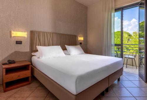 a bedroom with a large white bed and a balcony at Hotel Acapulco in Forte dei Marmi