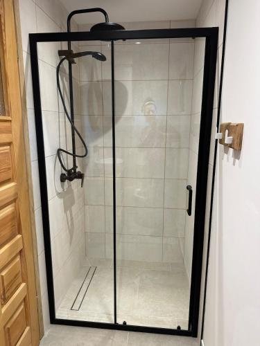 a shower with a glass door in a bathroom at Domek z balią in Zwierzyniec