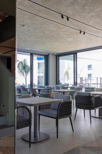 a dining room with tables and chairs and windows at Green Light Hotel in Ksamil