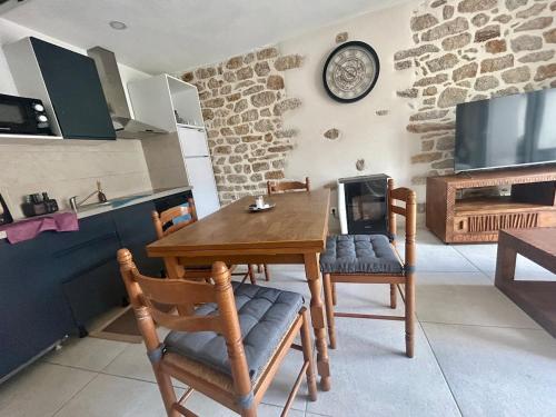 a table and chairs in a kitchen with a clock on the wall at Logement thérapie bien-être in Pont-lʼAbbé