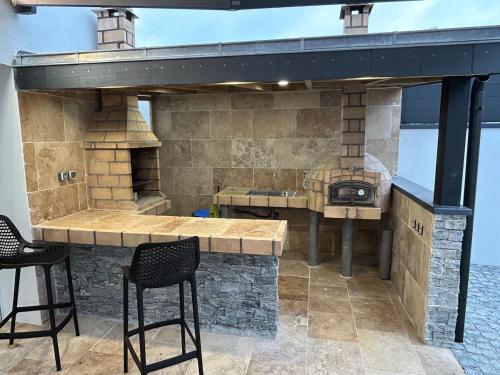 an outdoor kitchen with a stone counter and stools at Logement thérapie bien-être in Pont-lʼAbbé