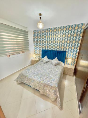 a bedroom with a bed with a blue head board at Résidence CaboBeach in Cabo Negro