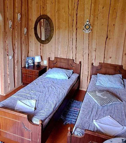 two twin beds in a room with wooden walls at Imantass in Salacgrīva