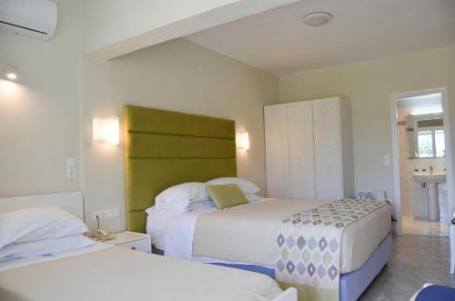 a bedroom with two beds and a green headboard at Odysseus Hotel in Paleokastritsa