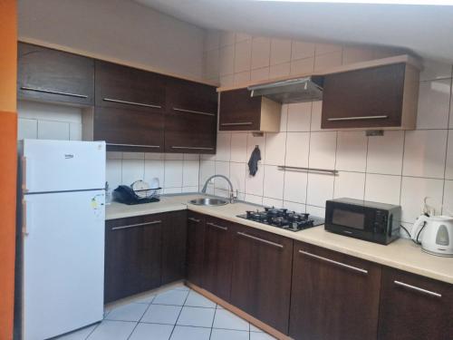 a kitchen with wooden cabinets and a white refrigerator at Apartament Pracowniczy in Pogórze