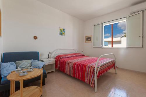 ein Schlafzimmer mit einem Bett und einem Tisch und einem Fenster in der Unterkunft Villino Raffy by BarbarHouse in Torre dell'Orso