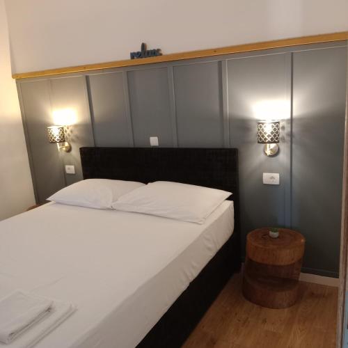 a bedroom with a white bed and two lights on the wall at VILA ROZA in Prožura