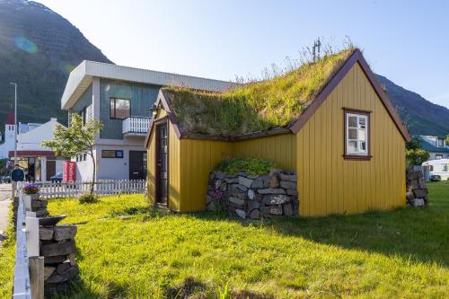 a yellow house with a grass roof on a hill at The Sigló House in Siglufjörður