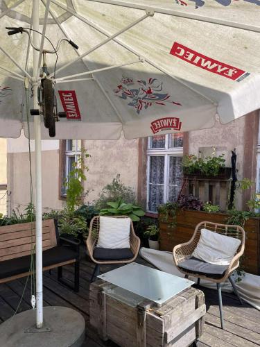 a patio with a white umbrella and chairs and tables at Apartamenty Smile in Grudziądz