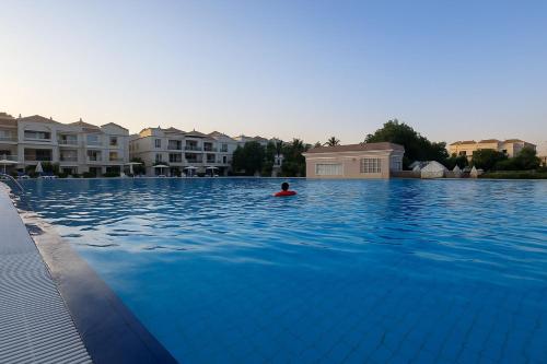 a person swimming in a large swimming pool at YODA Luxe Appartment, Yasmin-village in Ras al Khaimah