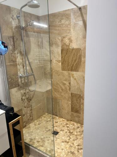 une douche dans une salle de bain avec une porte vitrée dans l'établissement Bord de mer, à Benerville-sur-Mer