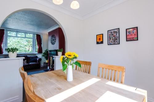 a dining room table with a vase of flowers on it at 3 BR Property in Prestwich 15 mins from Manchester City Centre Garden Free parking Superfast WIFI Netflix in Manchester