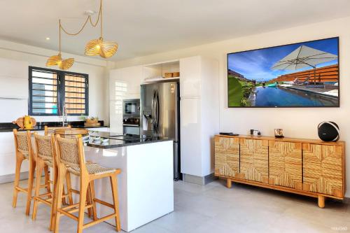 a kitchen with a refrigerator and a counter with chairs at Villa Kintana - Piscine - SPA - Prestations 5 Etoiles in Petite Île