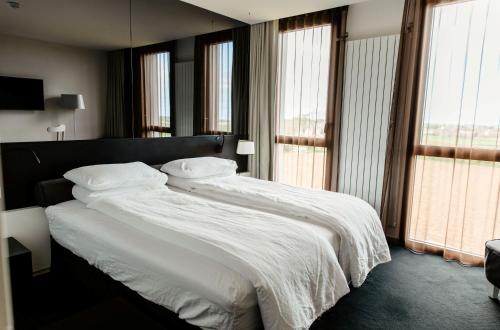 a bedroom with a large bed with white sheets and pillows at La Butte in Plouider