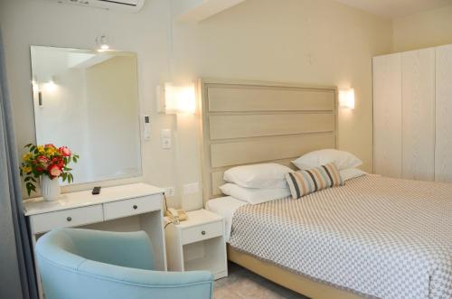 a bedroom with a bed and a mirror and a chair at Odysseus Hotel in Paleokastritsa