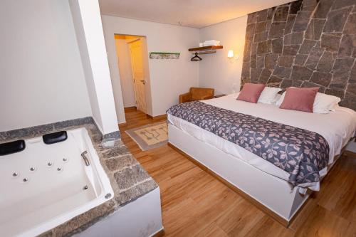a hotel room with a bed and a bath tub at Villa Hegus chales com hidro ar lareira in Campos do Jordão