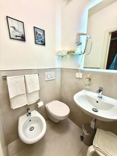 a bathroom with a white toilet and a sink at Villa Le Camelie Siena in Siena
