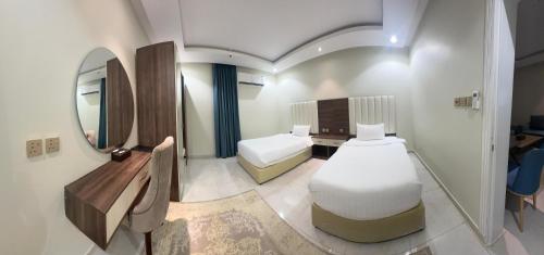 a small room with two beds and a mirror at شقق أزهار النرجس للشقق الفندقية in Umm al Khashab