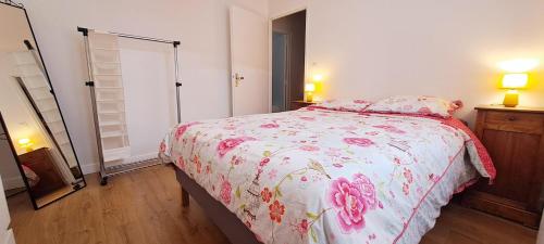 une chambre avec un lit avec un couvre-lit fleuri dans l'établissement Appartement calme, hypercentre, au pied du marché, à Rochefort