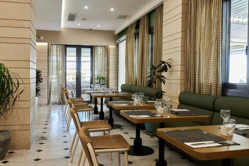 a restaurant with wooden tables and chairs and windows at Sentido Kyknos Beach Adults Only in Malia