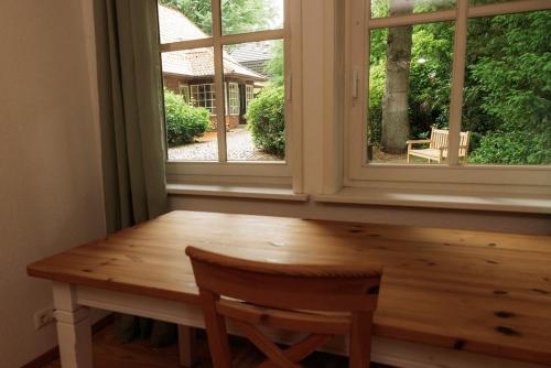 a wooden table and a window with a wooden chair at Schönstes kleines Ferienhaus in der Lü-Heide in Egestorf