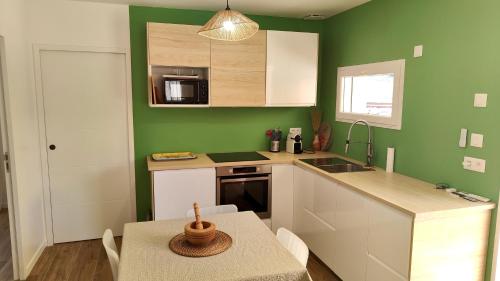 une cuisine avec des murs verts et une table avec un bol dessus dans l'établissement Lou et Line, à Lorgues
