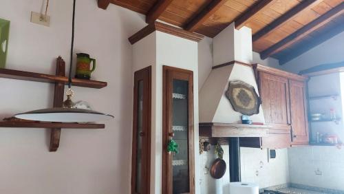a kitchen with wooden cabinets and a clock on the wall at Casa nel Parco delle Foreste Casentinesi in Moggiona