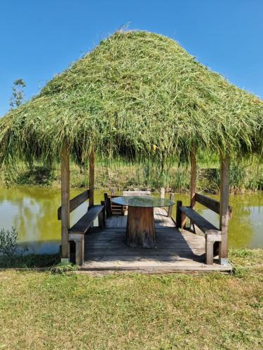 a picnic table with benches and a grass roof at La Ionicã Rozavlea MM in Rozavlea
