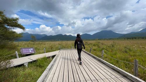 a person walking on a wooden boardwalk at Sanga Nikko in Nikko
