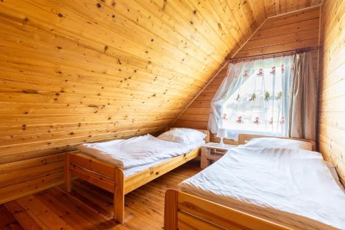 two beds in a wooden room with a window at Korsarz in Rusinowo